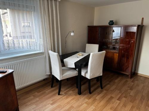 a dining room table with white chairs and a window at Ferienwohnung Nachtigall in Burg