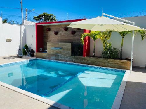 a swimming pool with an umbrella and an outdoor fireplace at Alcobaça Beach House in Alcobaça