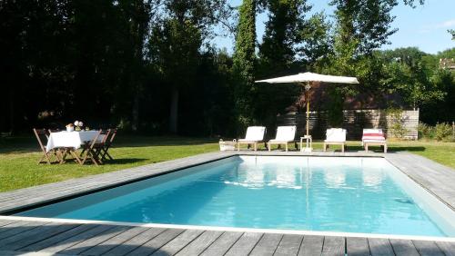 une piscine avec des chaises et un parasol dans l'établissement Superbe grange en Dordogne, au cœur de Trémolat, à Trémolat