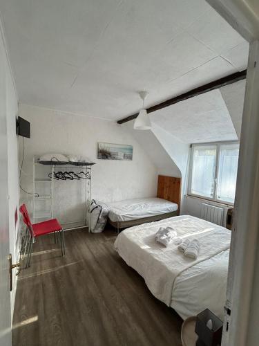 une chambre avec deux lits et une chaise rouge dans l'établissement Résidence proche des plages , route de loctudy, à Pont-lʼAbbé