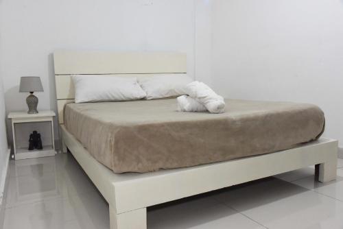 a white bed with a white stuffed animal on it at Hostel Gato Colonial in Santo Domingo