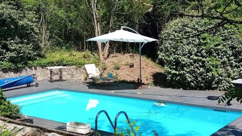 une piscine avec un parasol, une table et des chaises dans l'établissement Maison de charme avec vue exceptionnelle, à Monteils