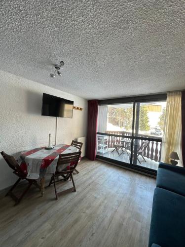 un salon avec une table et des chaises et un balcon dans l'établissement Charmant appartement, à Les Deux Alpes