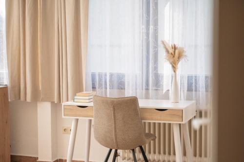 a desk with a chair in front of a window at Atelier Guesthouse in Filderstadt