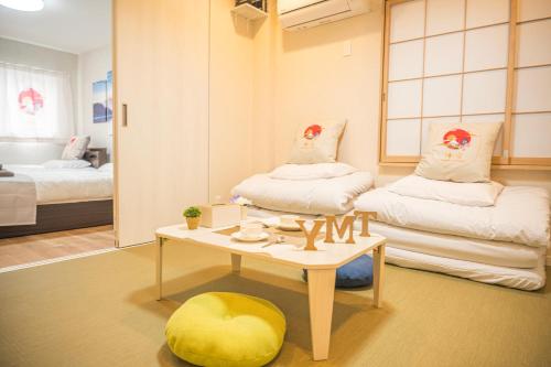 a room with two beds and a table and a yellow ottoman at 和の宿ホテルYamatoinn Akihabara#301 in Tokyo