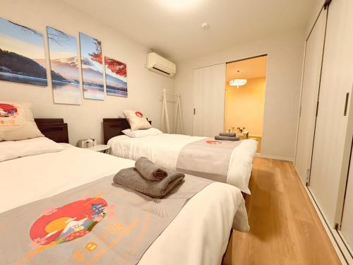 a bedroom with two beds with white sheets at 和の宿ホテルYamatoinn Akihabara#301 in Tokyo