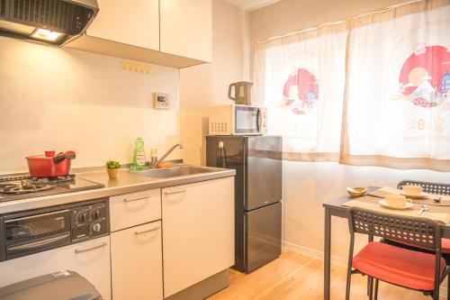 a kitchen with a sink and a refrigerator and a table at 和の宿ホテルYamatoinn Akihabara#301 in Tokyo
