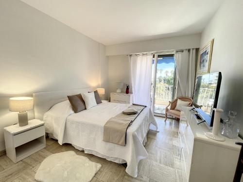 une chambre avec un lit blanc et une grande fenêtre dans l'établissement Emplacement idéal, terrasse vue mer 321L SEB, à Cannes