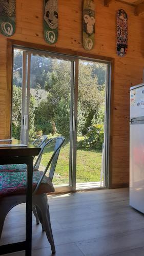 a kitchen with a table and a refrigerator and a window at La Cabana de Cocholgüe 45 in Tomé