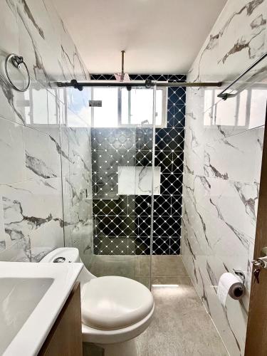 a bathroom with a toilet and a glass shower at Apto 301a - Estrena hermoso y cómodo apto con balcón - Casa Orquídeas in Fusagasuga