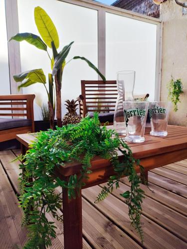 une table en bois avec des plantes vertes sur une terrasse dans l'établissement Le gite d'Arsène avec terrasse et garage en option a 200 m de la plage, à Étretat