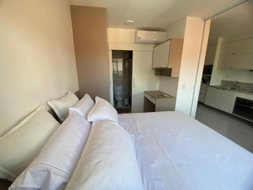 Una cama en una habitación con almohadas blancas. en Pouso do encanto, en Salvador