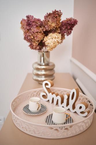 a tray with two cups and a vase with flowers at Apartamenty Centrum Sobieski in Wałbrzych