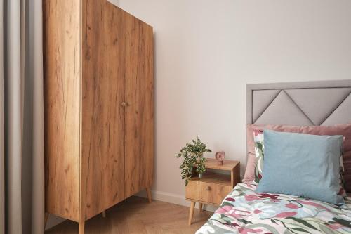 a bedroom with a wooden cabinet next to a bed at Apartamenty Centrum Sobieski in Wałbrzych