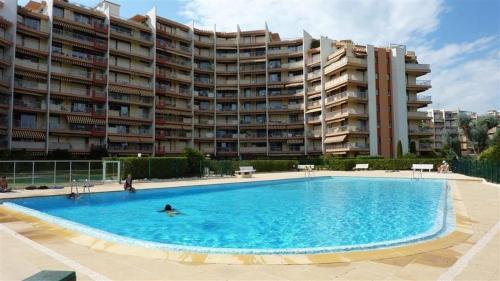 une grande piscine en face d'un grand immeuble dans l'établissement Joli appartement en résidence avec piscine et gardien, à Mandelieu-la-Napoule