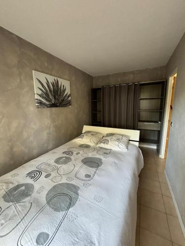 - une chambre avec un grand lit et un couvre-lit blanc dans l'établissement Joli appartement en résidence avec piscine et gardien, à Mandelieu-la-Napoule