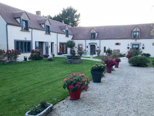 a house with potted plants in front of a yard at La Couarderie in Tigy