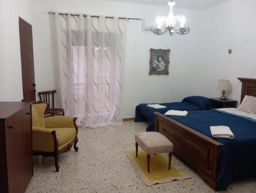 a bedroom with two beds and chairs and a chandelier at Elico Di Sicily B@B in Sambuca di Sicilia