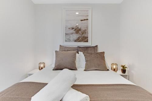 a bedroom with a large white bed with pillows at Takapuna Central Stylish 2BR Carpark Aircon in Auckland