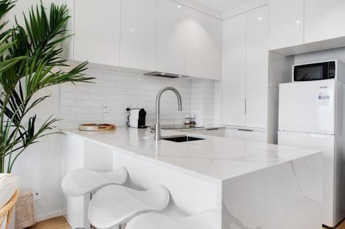 a white kitchen with white cabinets and white appliances at Takapuna Central Stylish 2BR Carpark Aircon in Auckland