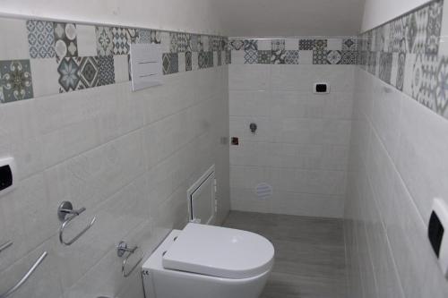 a white bathroom with a toilet and tiles on the wall at Gelsomino I in Ustica