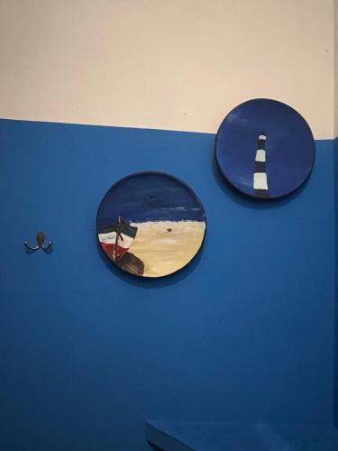 two plates on a blue wall with a picture of a lighthouse at Buena Onda Backpackers in San Juan del Sur