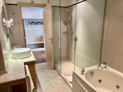 a bathroom with a shower and a tub and a sink at Unico Hotel in Ossona