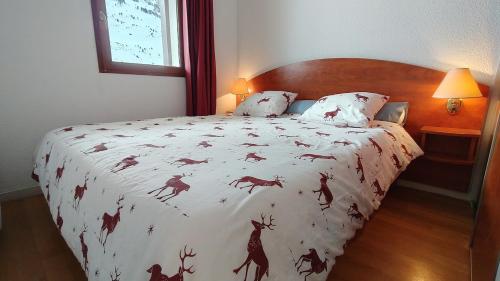 - un lit avec une couette blanche et un cerf dans l'établissement T2 piscine, terrasse, parking couvert Résidence Pic du Midi, à Bagnères-de-Bigorre