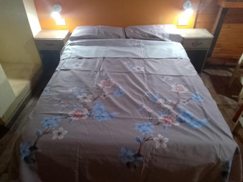 a bed with a white comforter with flowers on it at Brisas in Jardín América