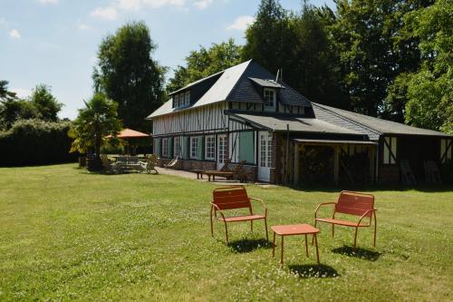 deux chaises assises dans l'herbe devant une maison dans l'établissement Chaleureux cottage normand en zone Natura 2000, à Freneuse-sur-Risle