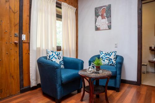 a living room with two blue chairs and a table at Tierra Buena Countryside Hotel in Monteverde Costa Rica