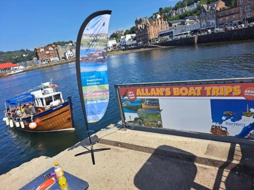 a boat trips sign with a boat in the water at Tawny Owl Pod with Hot Tub in Oban