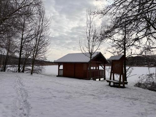 a small cabin in the snow next to a body of water at Chata u rybníka Machčák in Třebušín