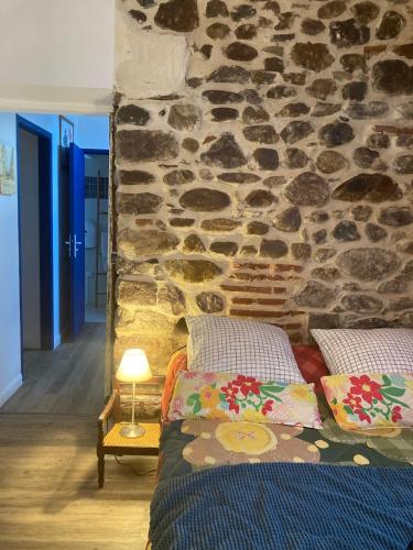 Cette chambre dispose de 2 lits en face d'un mur en pierre. dans l'établissement Appartement entier, terrasse, 4 personnes sur le GR10, à Saint-Étienne-de-Baïgorry