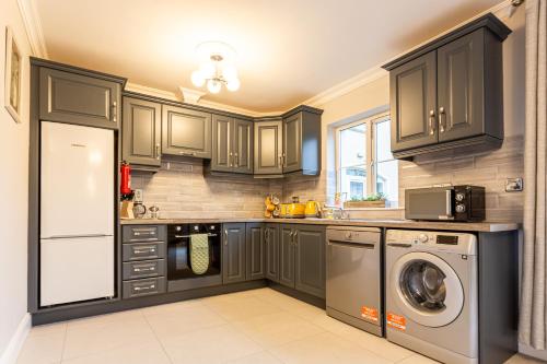 a kitchen with gray cabinets and a washer and dryer at No 20 Killarney Holiday Village in Killarney