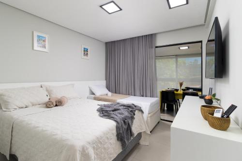 Habitación blanca con 2 camas y escritorio. en Design & Conforto Praia aos seus Pés Flats Mauê, en Tamandaré