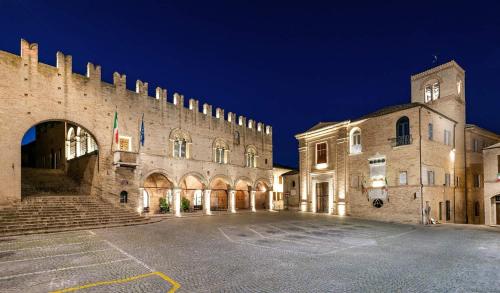a large stone building with a clock tower at night at La Dimora del Borgo in Montecassiano