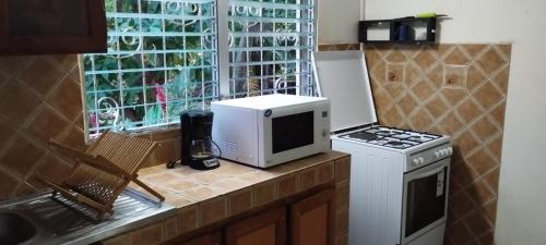 a kitchen counter with a microwave and a stove at Maison traditionnelle créole in Deshaies