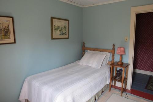 a bedroom with a bed with white sheets and a lamp at Devil's Cove in Port Rexton