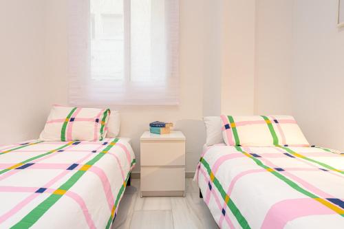a bedroom with two beds and a night stand at Mi Casa es Tu Casa - Malaga Center - Fiber WiFi in Málaga
