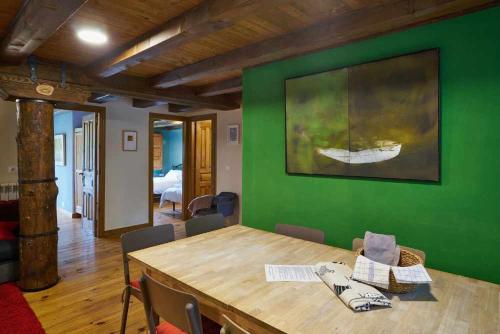 a dining room with a green wall and a wooden table at Casa Pirineos ambos apartamentos in Ulle