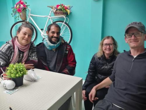 a group of three people sitting at a table with a bike at Hostal las margaritas in Pasto
