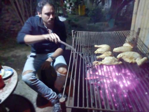a man is cooking food on a grill at Hostal las margaritas in Pasto