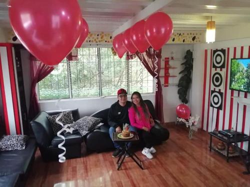 two people sitting on a couch in a room with balloons at Hostal las margaritas in Pasto