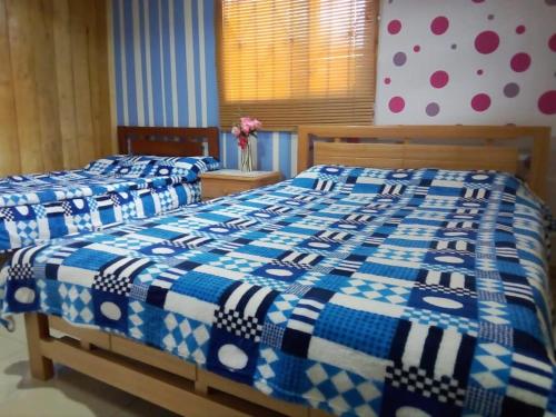 two beds in a bedroom with a blue and white blanket at Hostal las margaritas in Pasto