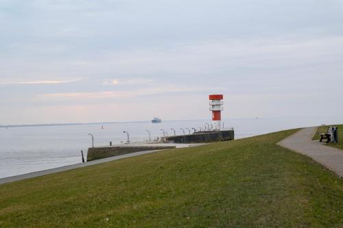 a pier with a lighthouse next to the water at Ferienwohnung Hygge und Mee-h-r in Brunsbüttel