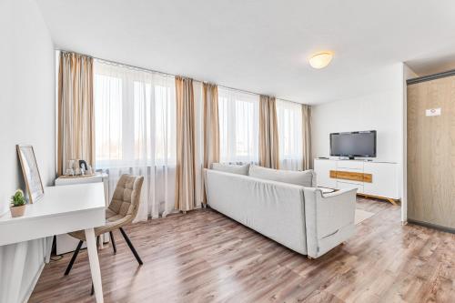 a living room with a couch and a desk and a tv at Atelier Guesthouse in Filderstadt