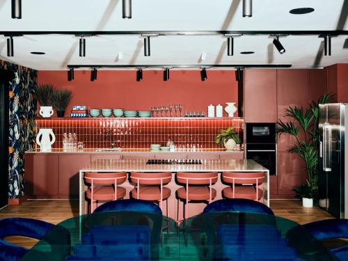 un bar con paredes rojas y sillas azules en Vertus Edit Canary Wharf, en Londres