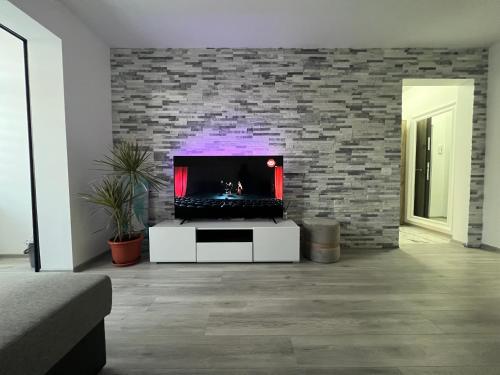 a living room with a tv and a brick wall at ADI-RENTS Apartmens in Giurgiu
