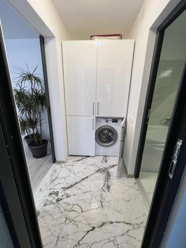 a laundry room with a washer and dryer on a marble floor at ADI-RENTS Apartmens in Giurgiu
